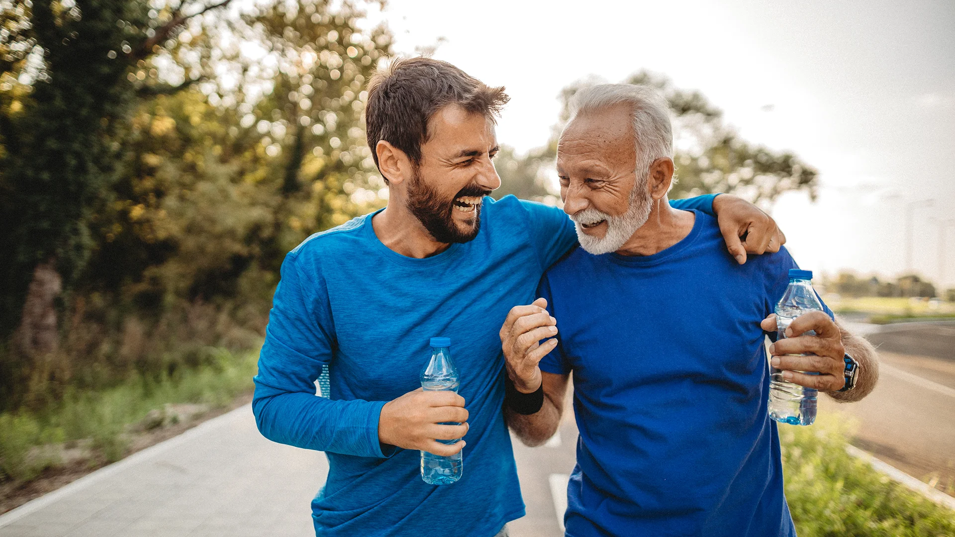 A young man and an elderly man laughing and holding a water bottle (photo)