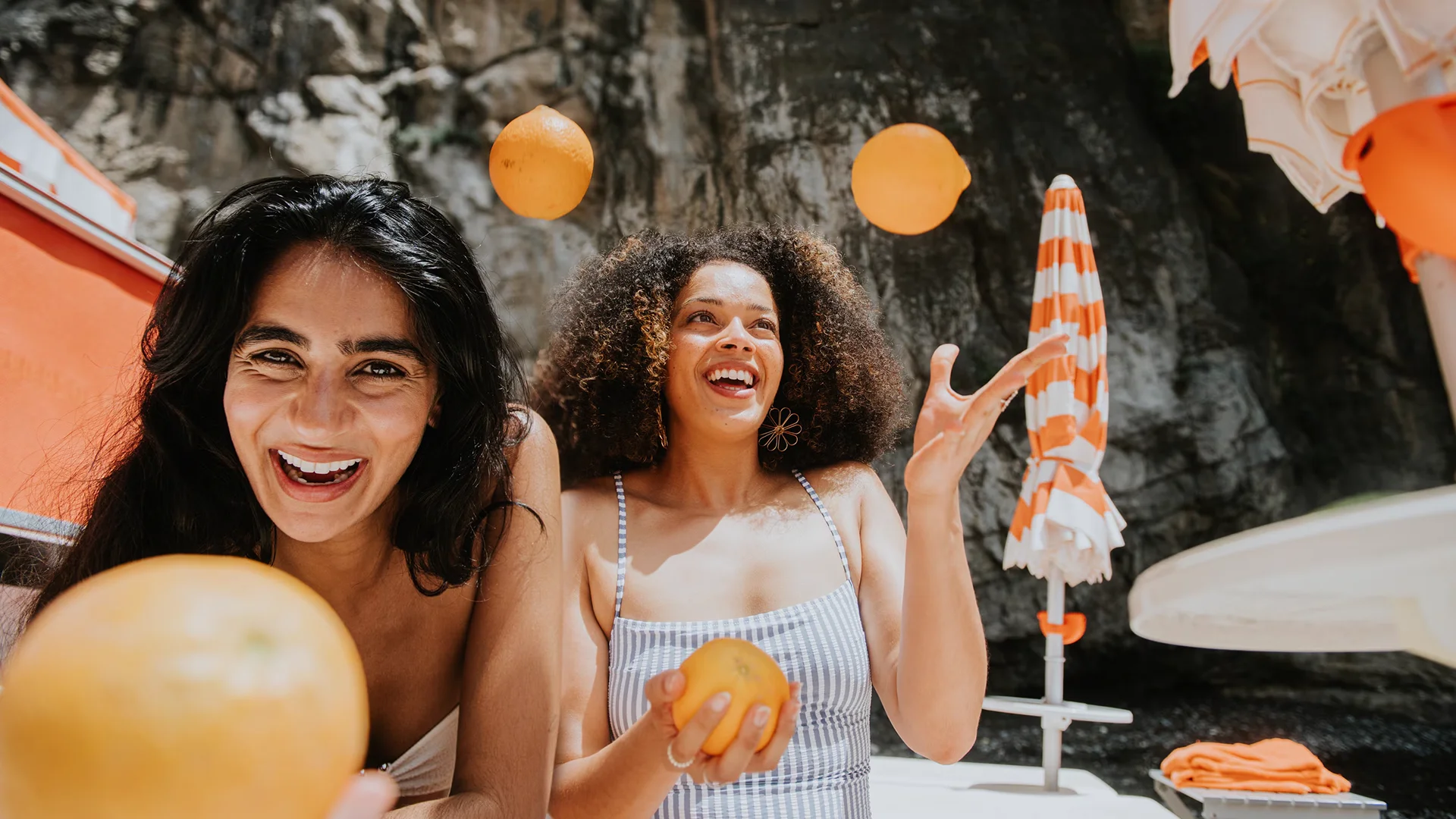 Two women holding oranges and laughing (photo)