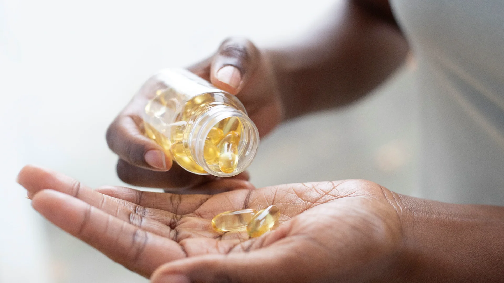 A person holding a glass full of yellow pills (photo)