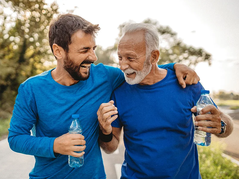 A young man and an elderly man laughing and holding a water bottle (photo)