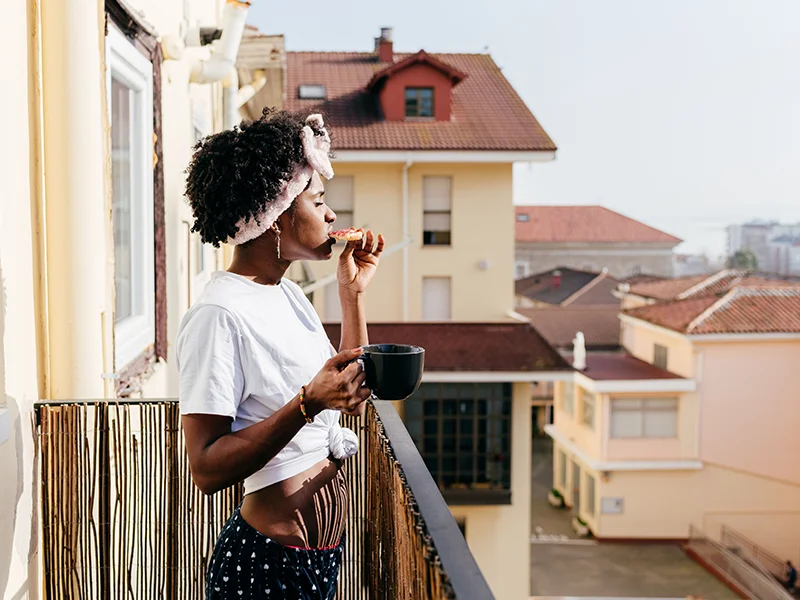 A young woman on a balcony drinking coffee (photo)