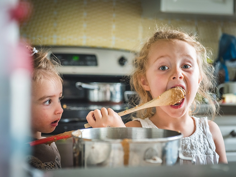 Two young children stand in a kitchen. (photo)