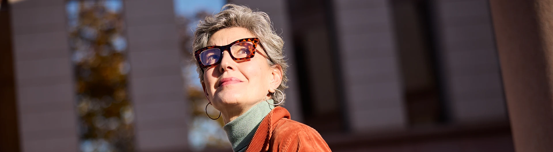 A woman wearing sunglasses, looking upward outdoors. (photo)
