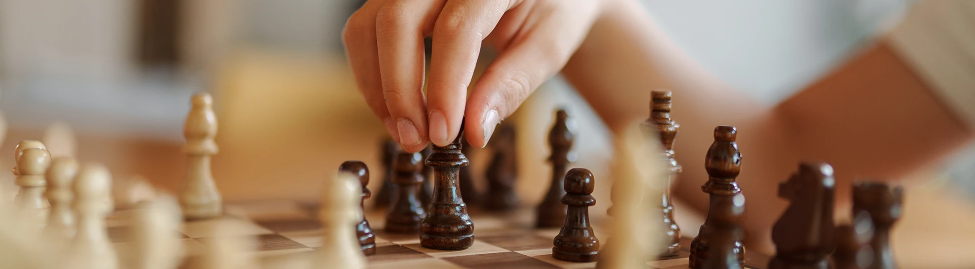 A hand moving a chess piece on a chessboard. (photo)