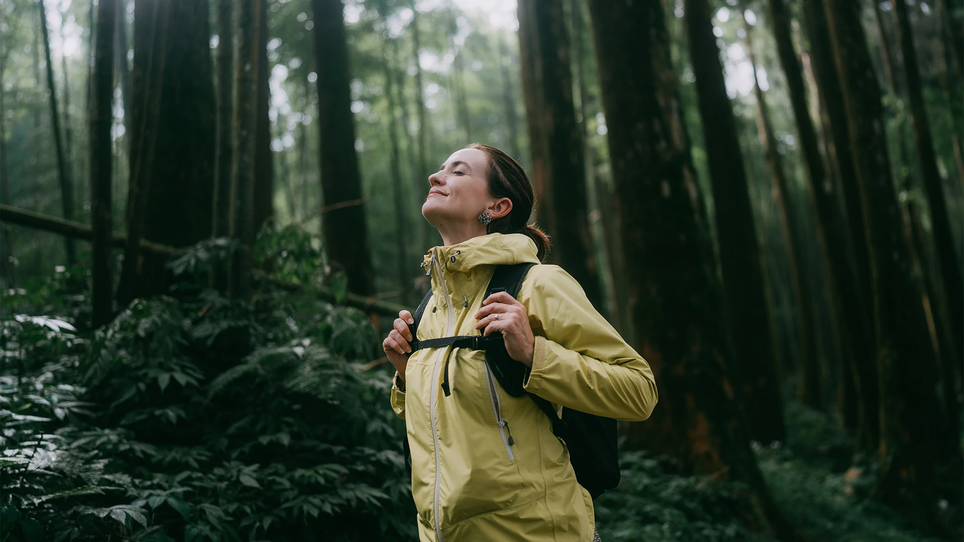 A woman pausing in a forest, breathing in nature and calm. (photo)