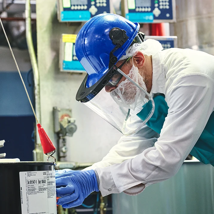 Factory worker wearing protective gear operating industrial equipment. (photo)