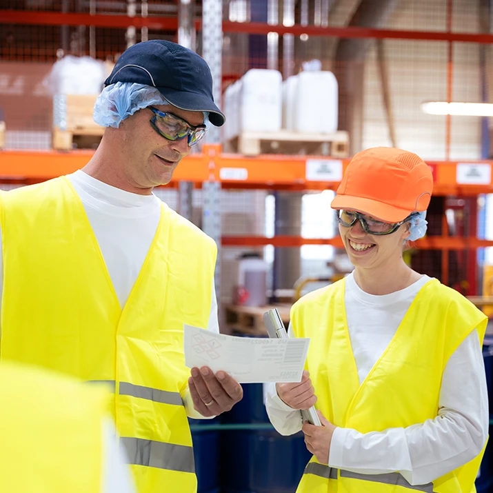 Two colleagues smiling and talking indoors. (photo)