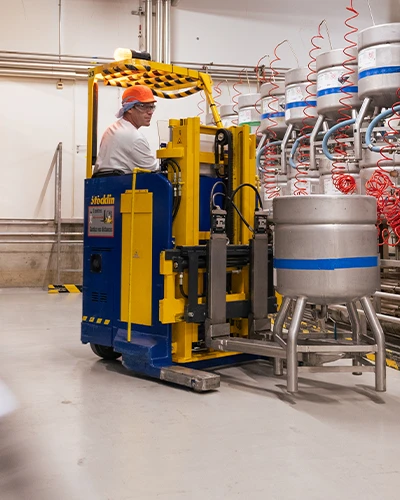 Worker driving a small industrial vehicle inside a factory. (photo)