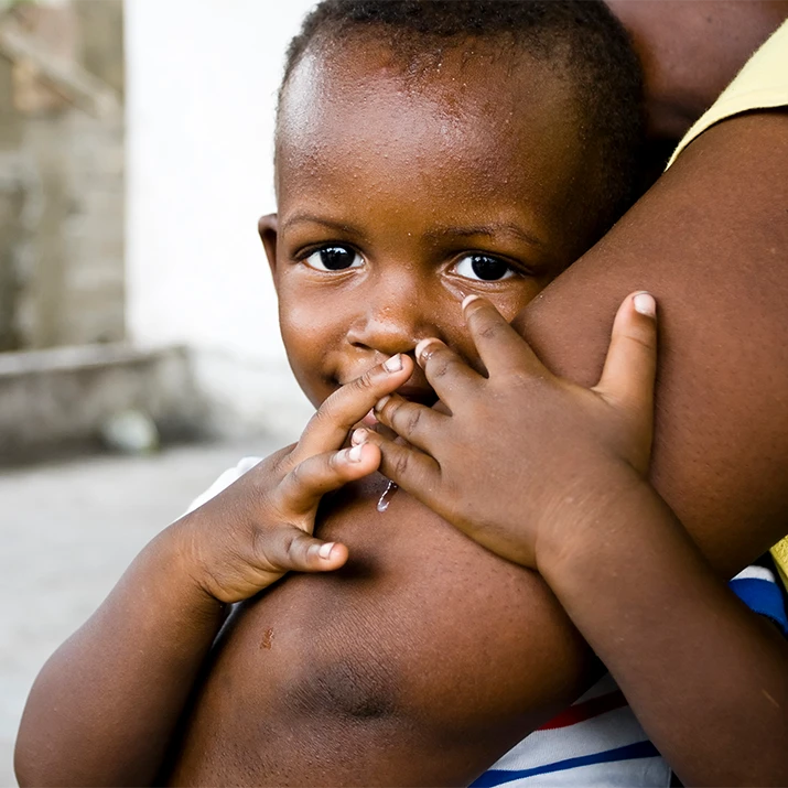 Young child resting against an adult’s arm. (photo)