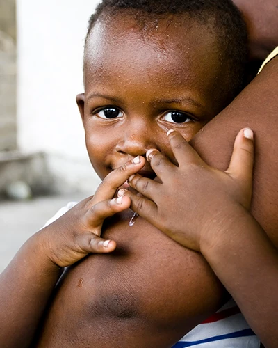 Young child resting against an adult’s arm. (photo)